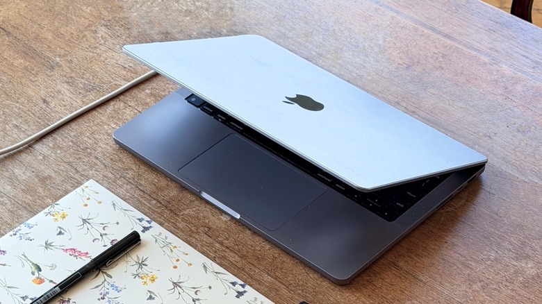 A close-up shot on a half-closed MacBook Pro on a wooden table