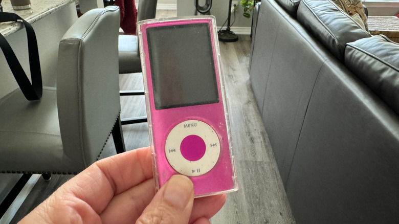A hand holding a pink iPod Nano