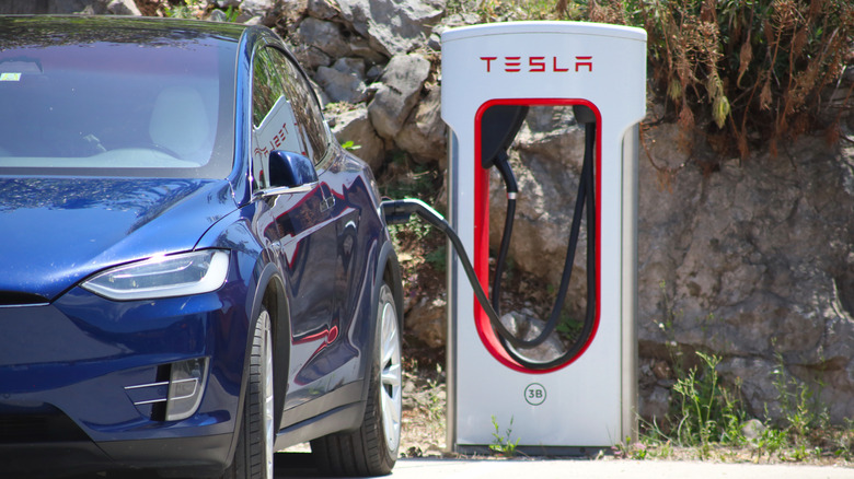 A Tesla vehicle connected to a Tesla Supercharger interface.