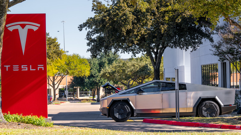 Tesla Cybertruck parked next to dealership logo sign