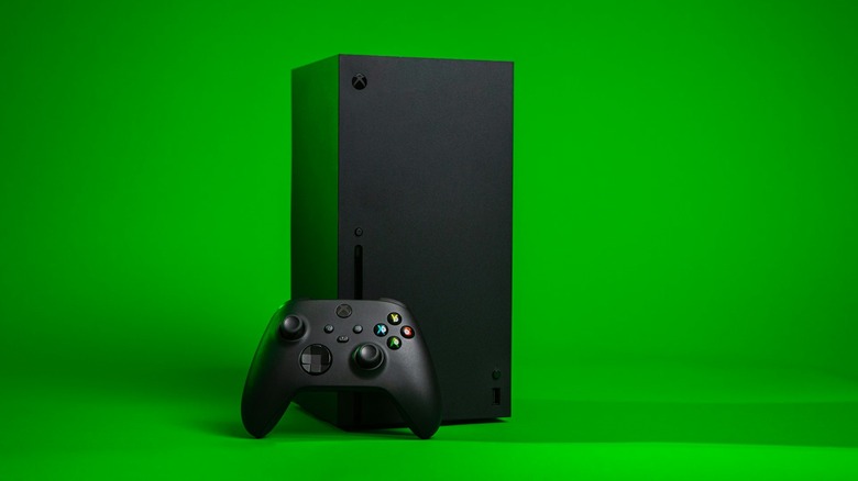 Xbox Series X next to controller and bright green background.