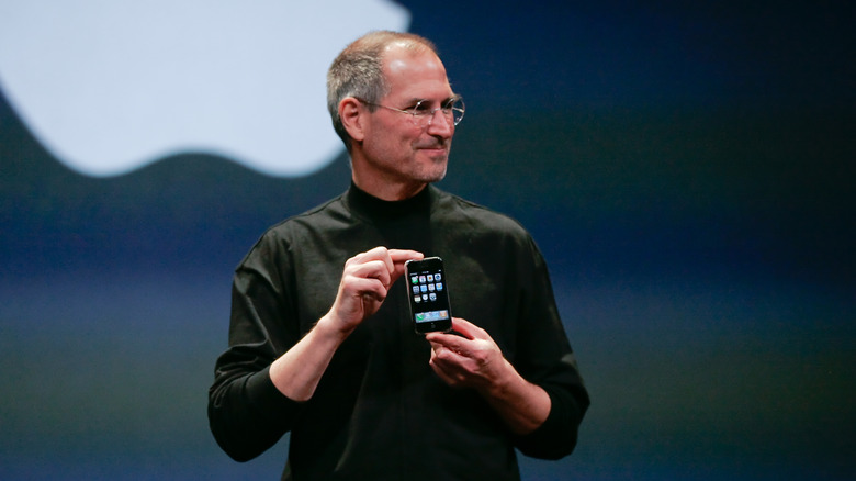 Steve Jobs holding the original iPhone.