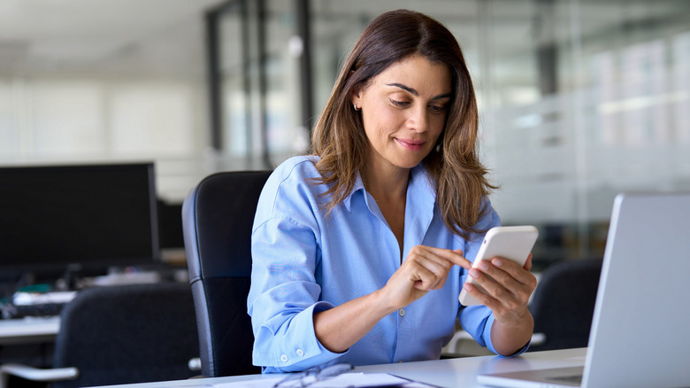 a woman interacting with her smartphone in an office