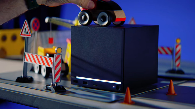 Person playing with toy car on top of Valve Steam Machine.