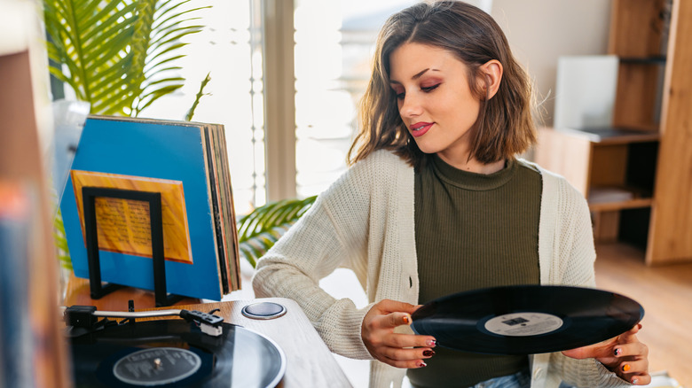 A woman playing a record on a record player.