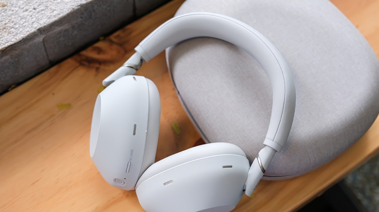 A pair of white Sony WH-1000XM6 headphones on a wooden surface