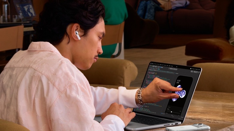 A man touching a MacBook Pro while working from a café