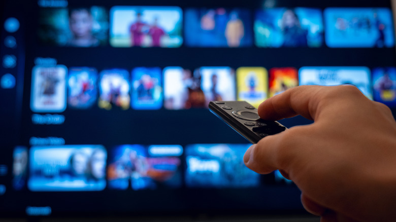 A hand using a remote to scroll through a streaming service.