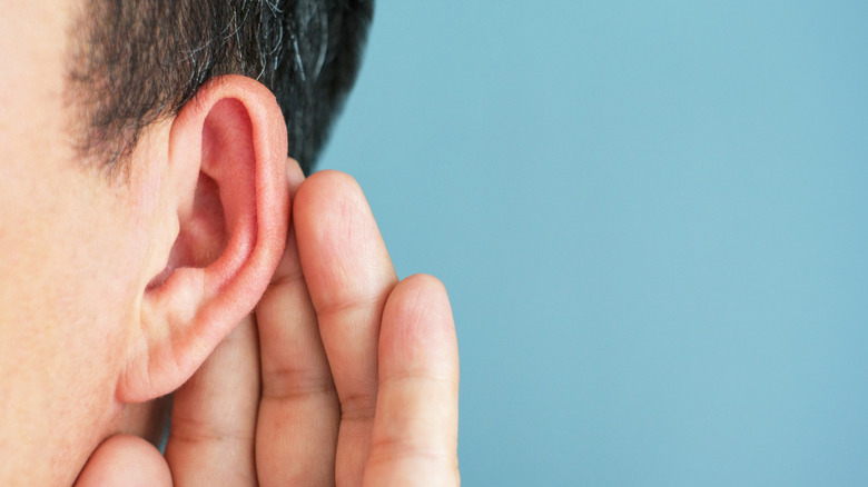 A person cupping their ear to hear better.