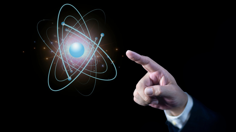 Finger pointing at the illustration of an atom