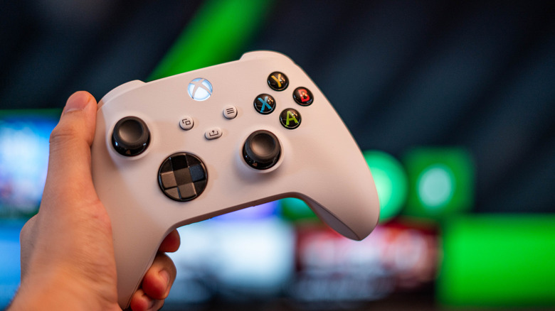 A hand holding a white Xbox controller
