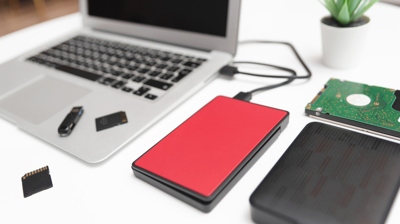 A laptop with multiple hard drives and storage solutions, including an SD card and a flash drive