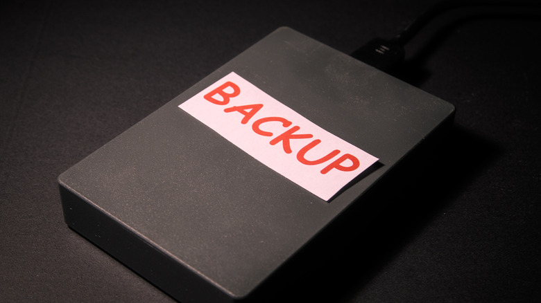 A black external hard drive with the word BACKUP written on a white label