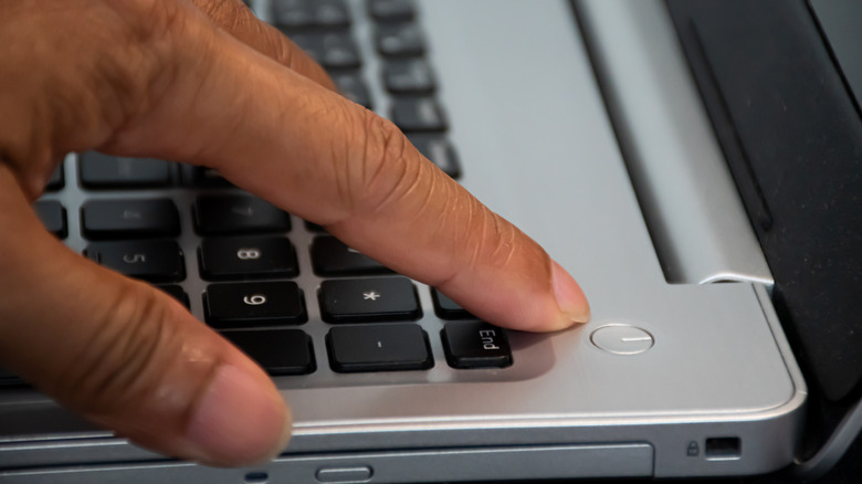 A picture of someone pointing at the power button on a laptop