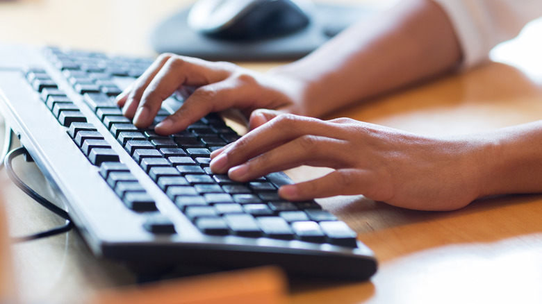 Close-up of hands in gloves cleaning keyboard