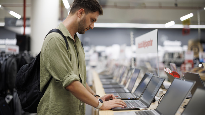 A man browsing laptops in an electronics store.