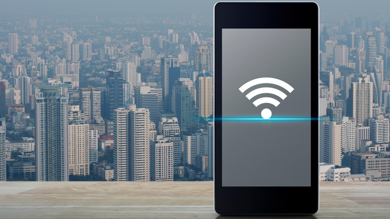 A phone with a Wi-Fi symbol on the screen against a cityscape in the background