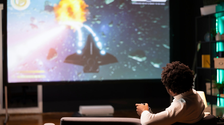 A person playing a video game on a massive TV screen