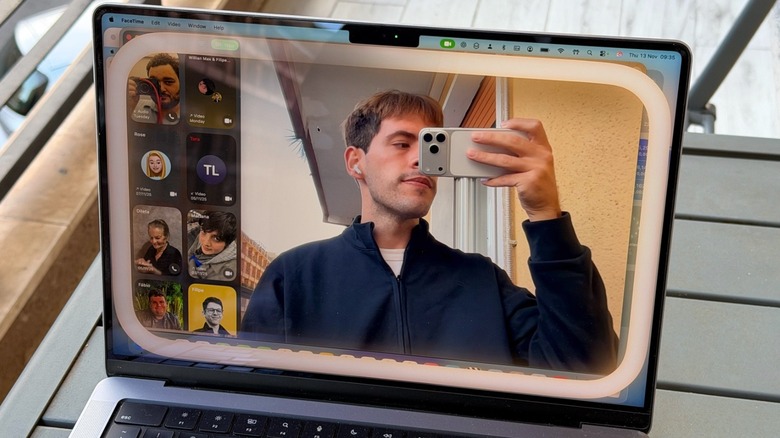 A man taking a photo of a MacBook Pro on a table with FaceTime on