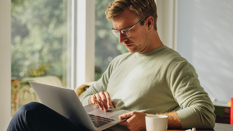 Man sitting at a table with a laptop in his lap