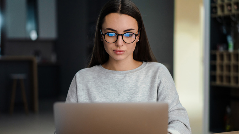 Woman in glasses looking at a laptop screen