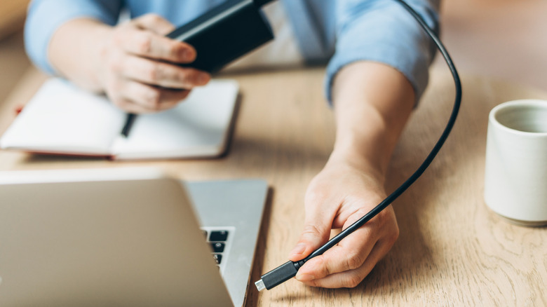 Person charging a laptop with a power bank.