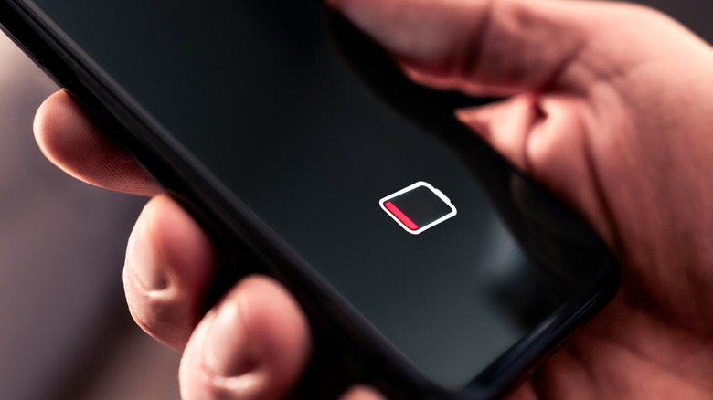 Close-up of a person holding a phone with low battery