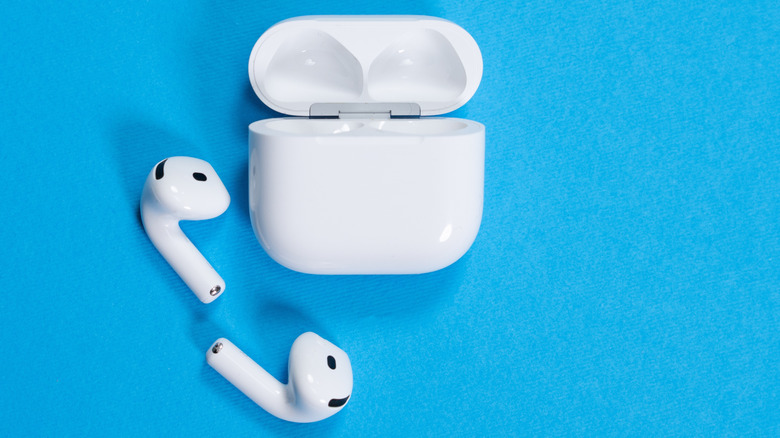 white Apple AirPods 4 wireless earbuds and open charging case on a vibrant blue background