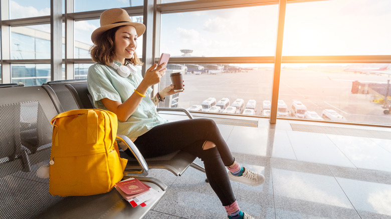 A young woman looks at her cell phone at an airport