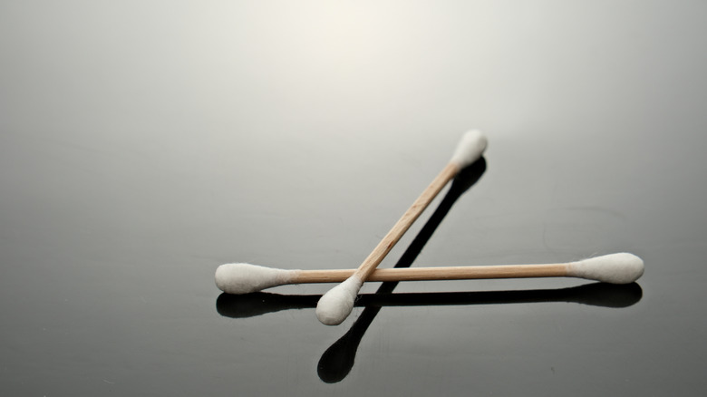 Two cotton swabs set against a gray backdrop.