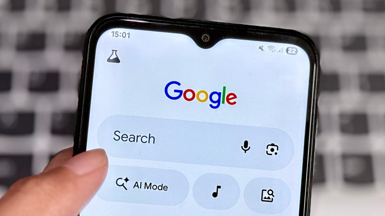 A person holding a phone with the Google search page open