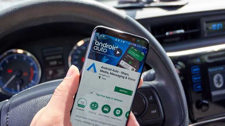 Android Auto app page on Google Play displayed on a smartphone screen in the car.