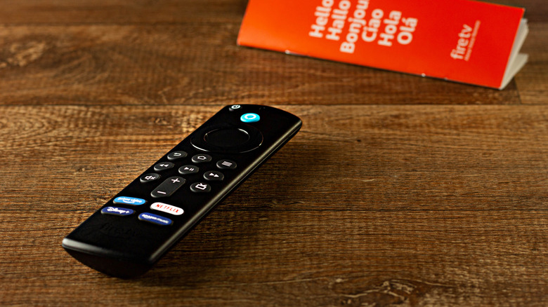 A Fire TV Stick remote lying on a tablet next to a paper manual