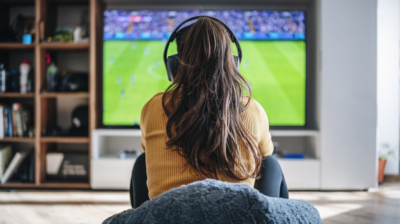 A woman sitting in front of a TV with headphones on