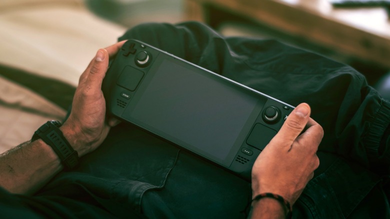 A man holding an unpowered Steam Deck in his lap