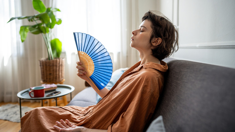 A woman using a fan to cool down on a hot summer day