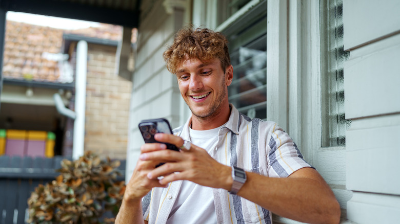 A man smiling as he looks at his phone screen