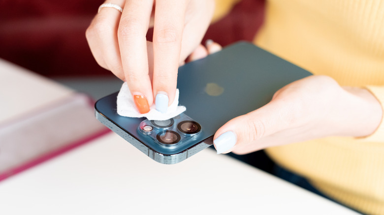 Hands wiping an iPhone with a wet wipe