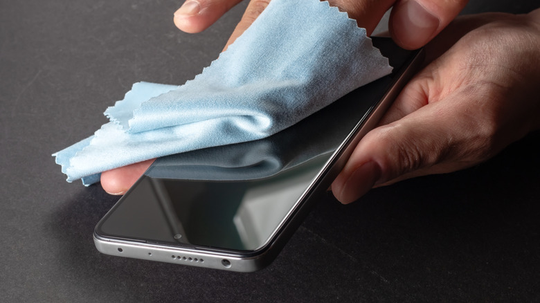 A person cleaning a phone with a cloth.