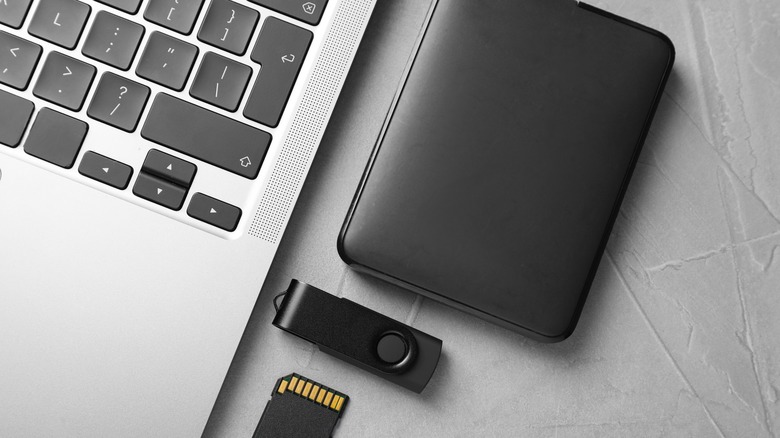 A laptop with a hard drive, flash drive, and memory card.