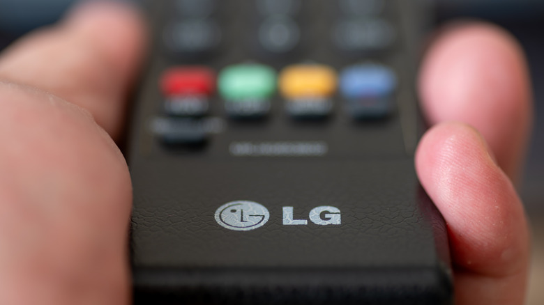 A close-up, blurred image of a person holding an LG TV remote.