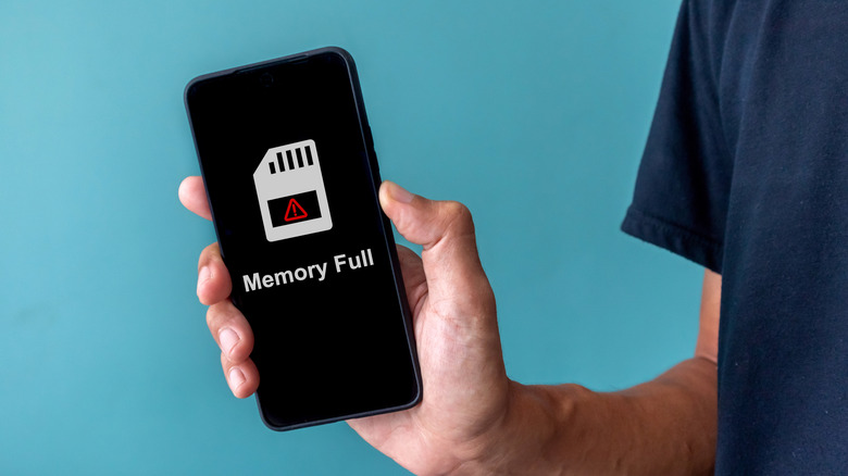 A person holding a smartphone with a full memory warning.