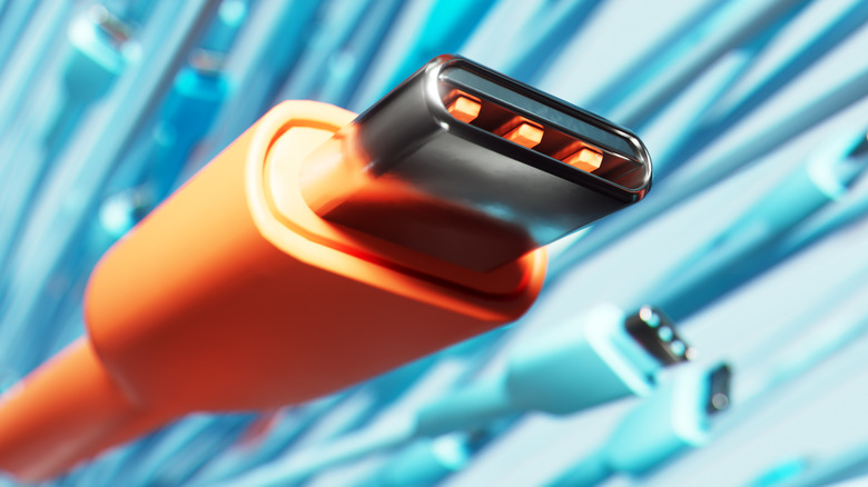 An orange USB-C cable with several teal-colored USB-C cables in the background