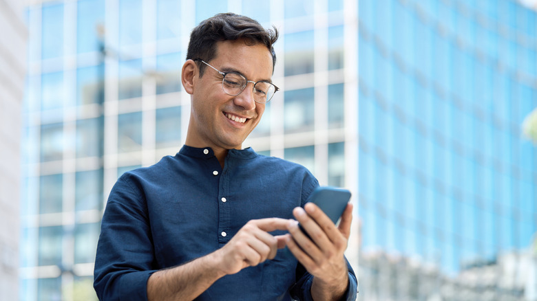A man using a smartphone outside in a city.