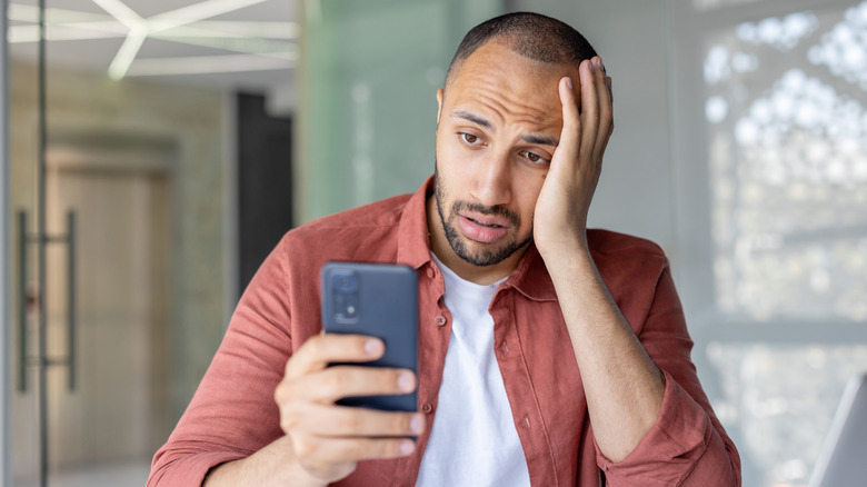 a man is looking at his Android in frustration