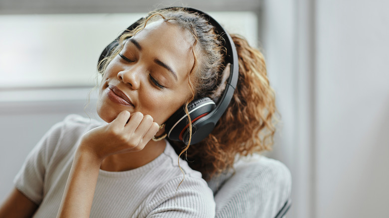 A woman sitting peacefully on the couch wearing headphones