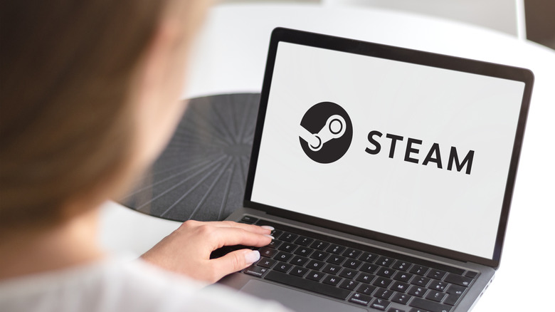 Woman at laptop displaying Steam logo