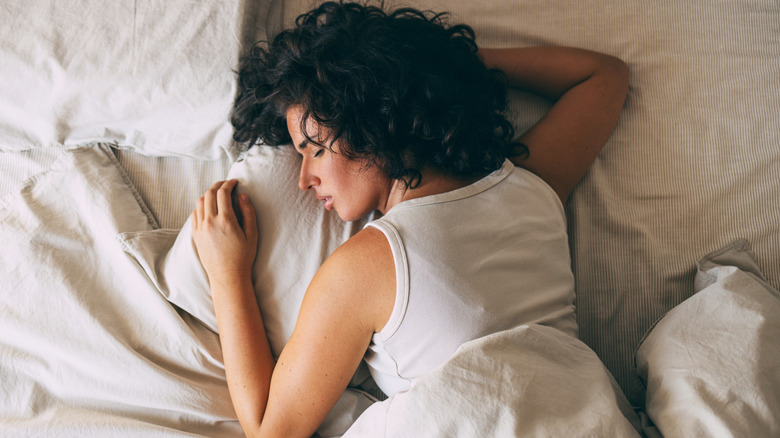 A woman lying on her stomach sleeping in bed.