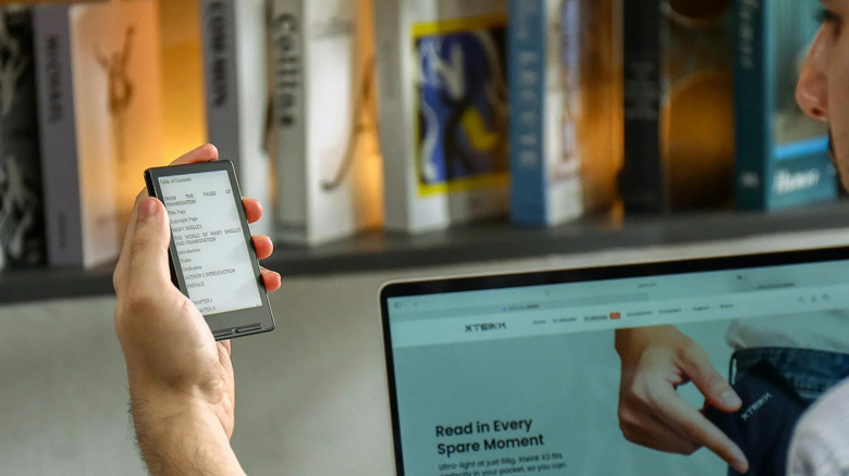 Person holding Xteink X3 while reading an e-book