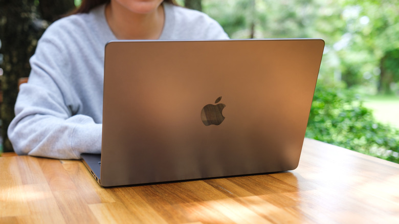 Woman using MacBook on wooden table outside